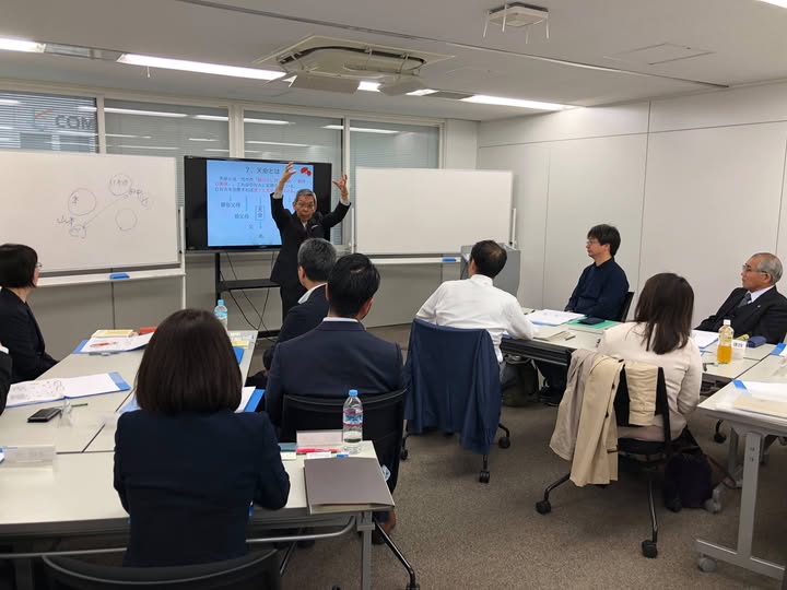 名誉講師天明茂がホワイトボードとモニターを背に塾生に向かって講義している様子