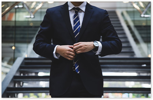 男性がスーツのボタンを留めて気を引き締めている様子