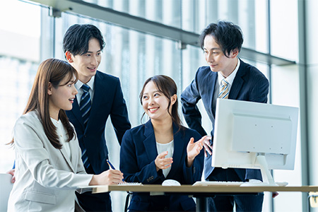 男女二人ずつ、計四人が1つのパソコンに向かって話し合っている様子